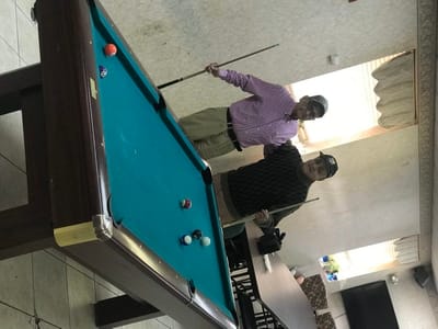 Two residents playing billiards in an activity room