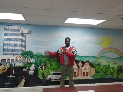 A person standing in front of a hand-painted mural in a common area
