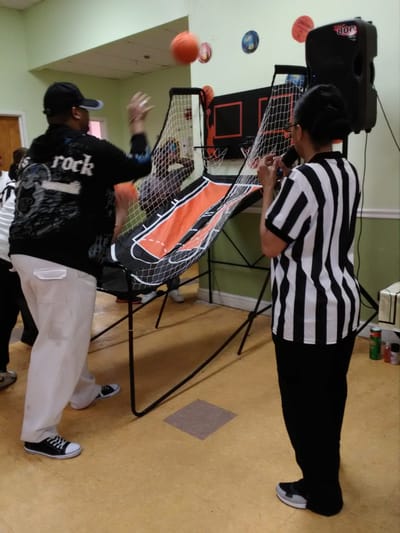 Residents enjoying a basketball arcade game in the activity room