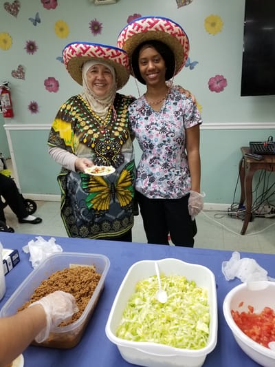 Residents and staff celebrating with food in colorful attire