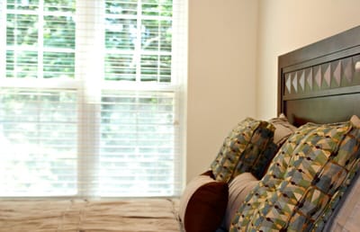 Cozy resident room with pillows and blinds.