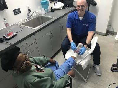 Staff assisting a resident with foot care in a treatment room