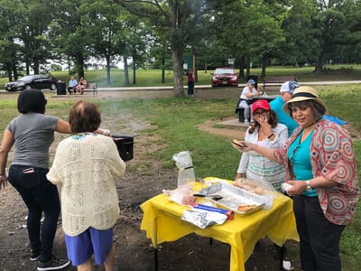 Residents and staff participating in a barbecue outdoors