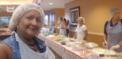 Residents and staff preparing food in a kitchen area