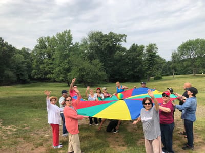 Residents enjoying an outdoor activity with a colorful parachute
