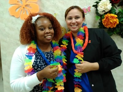 Two staff members wearing colorful leis and smiling