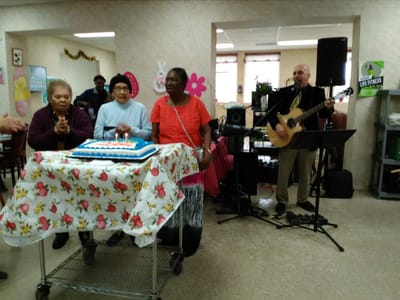 Residents celebrating a birthday with music and cake