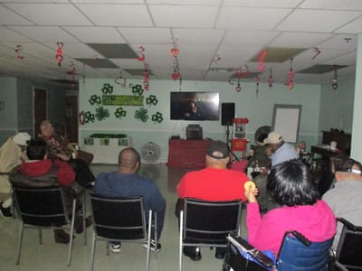 Residents watching a movie in a decorated activity room