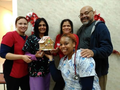 Staff members celebrating with a gingerbread house