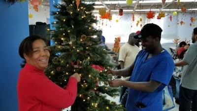 Residents and staff decorating a Christmas tree in a common area