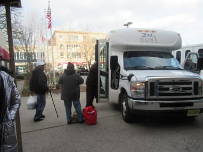 Residents boarding a facility shuttle outside the building