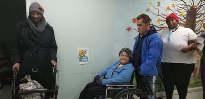 Residents and staff in a facility interior with a mural