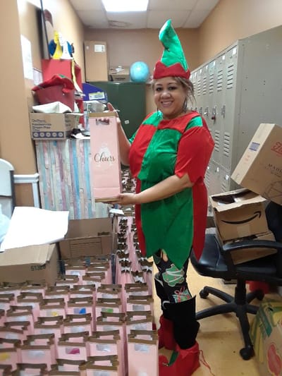 Staff member in festive attire holding gift bags