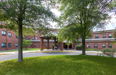 Entrance area of Aspen Hill Healthcare Center with trees and seating