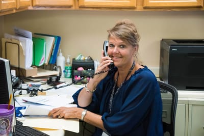 Staff member at reception desk answering phone