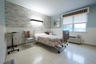 Private resident room with a hospital bed and chair