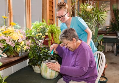 Resident gardening with staff assistance indoors