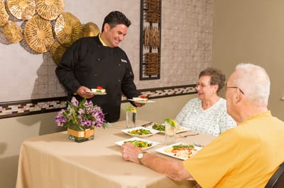 Catering staff serving meals to residents in a dining area