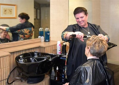 Stylist cutting the hair of a resident in a salon
