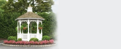 White gazebo surrounded by flowers in a garden setting