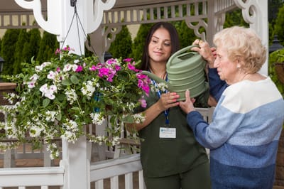 Staff assisting a resident with gardening in the outdoor area