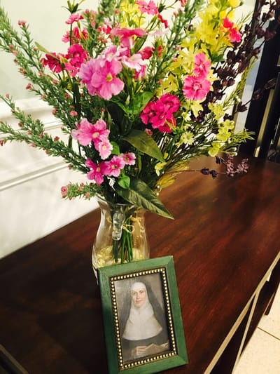 A vase of flowers with a portrait on a table