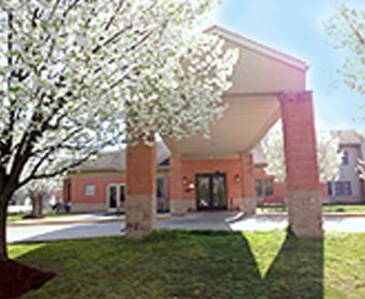 Exterior view of assisted living facility entrance with flowering trees