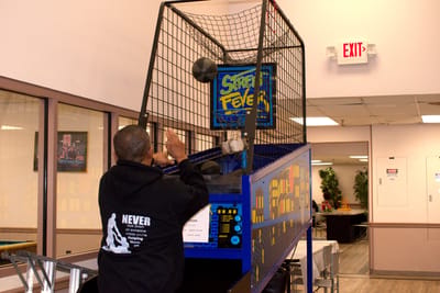 Resident playing a basketball arcade game in the activity room