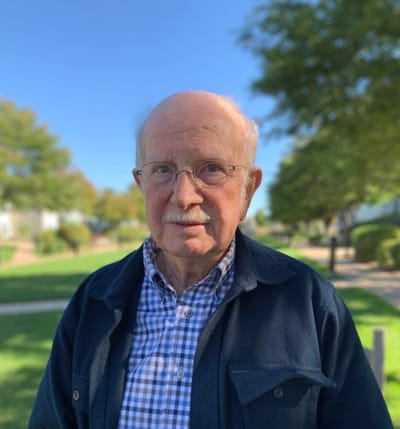 Elderly man standing in a green outdoor space