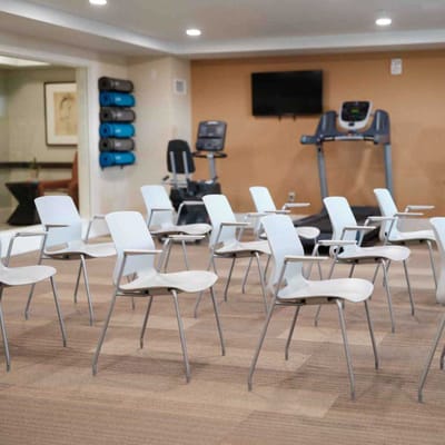 Interior of a fitness area with workout equipment and chairs