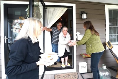 Residents receiving meals at the entrance of a facility
