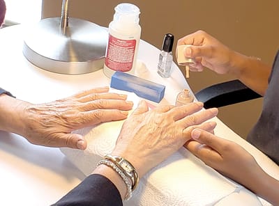 Two hands receiving manicure treatment in a bright room