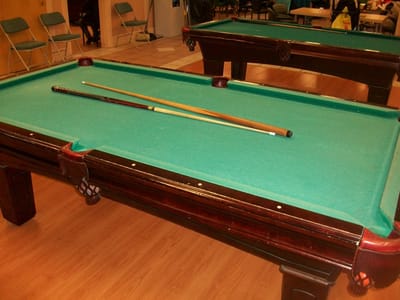 Billiards table with cues in a common area