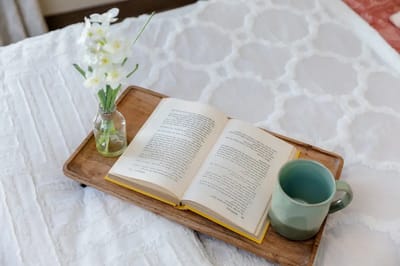 A book and a cup on a wooden tray