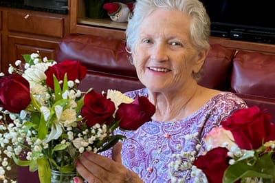 A resident smiling while arranging flowers indoors