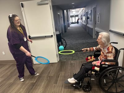 Staff member playing with resident in a hallway