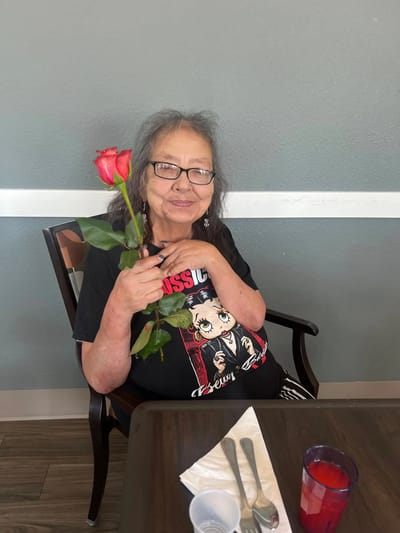 Resident holding a rose, smiling at the camera