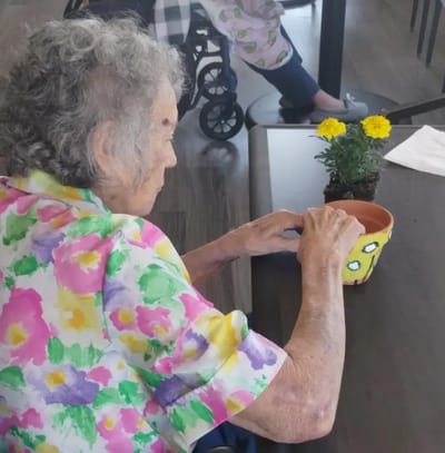 Resident potting a flower in a vibrant indoor setting