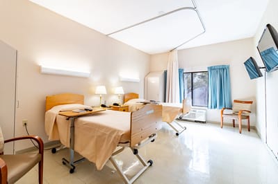 Two hospital-style beds in a bright patient room