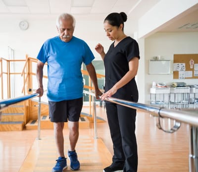 A resident practicing walking with a caregiver's assistance