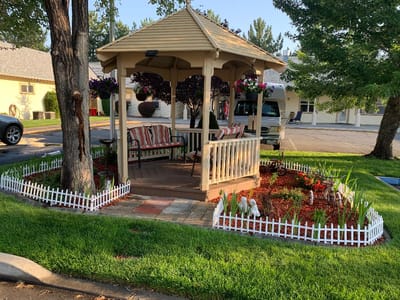 Outdoor gazebo with seating and flower beds
