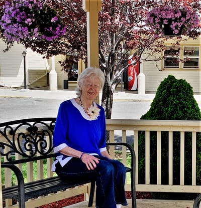 Elderly woman sitting on a bench in a garden area