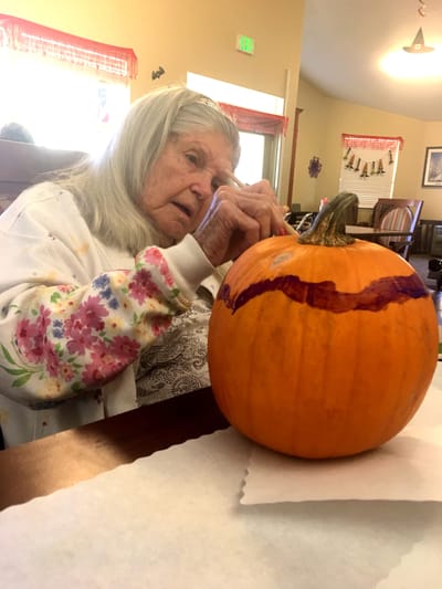 Resident painting a pumpkin during an activity