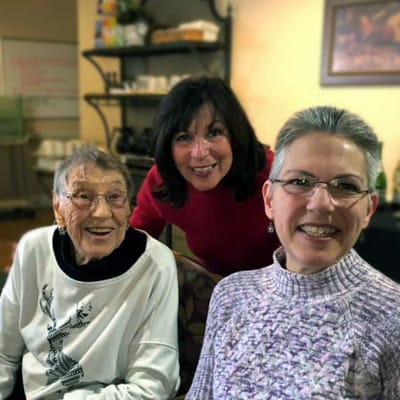 Three women smiling together in a cozy interior setting