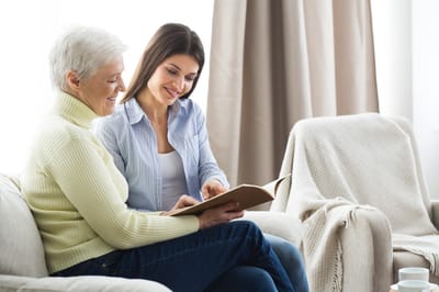 Two women reading together in a cozy living room