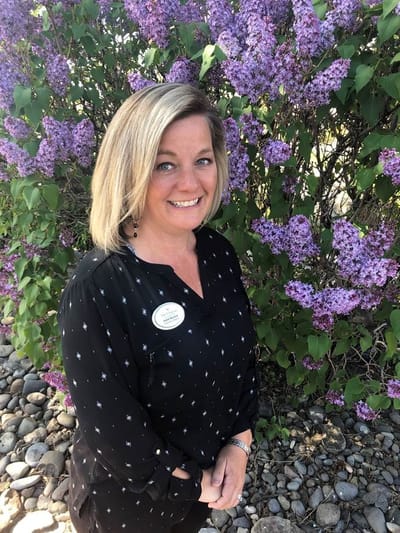 Staff member posed in front of blooming lilacs outside