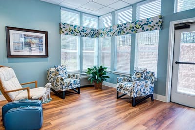Bright common area with floral chairs and large windows