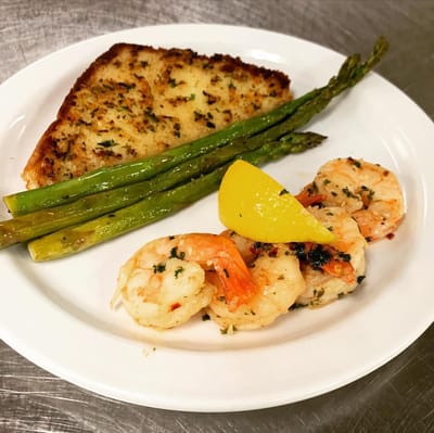 A plated meal with shrimp, asparagus, and garlic bread