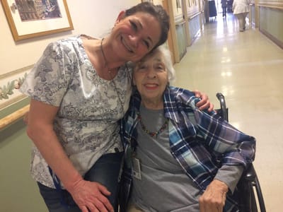 A staff member and resident smiling in a hallway