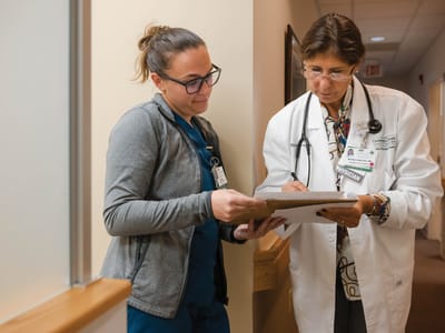 Two healthcare professionals discussing paperwork in a hallway